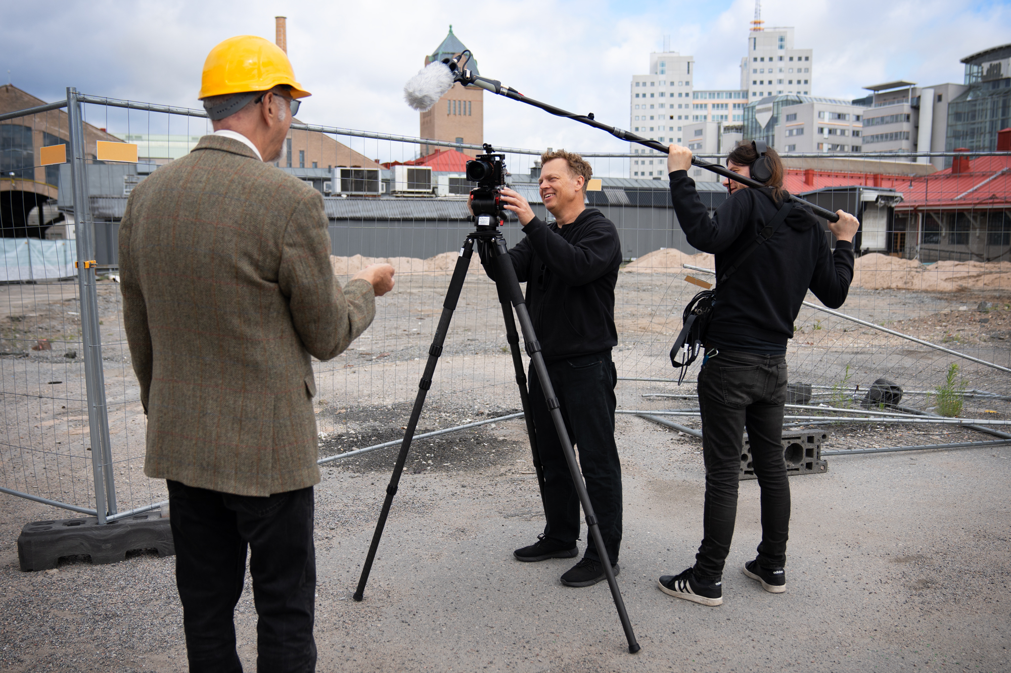 Fotograf och ljudtekniker filmar talare på byggarbetsplats