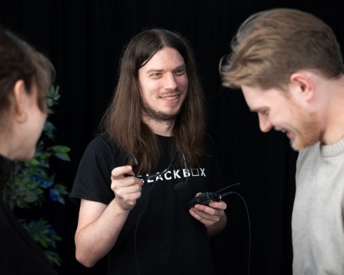 Ljudtekniker håller headset och pratar glatt med två personer